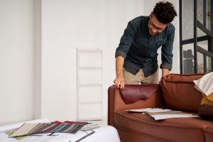 Man selecting fabric samples for sofa upholstery in modern living room — furniture reupholstery and fabric selection process in Dubai