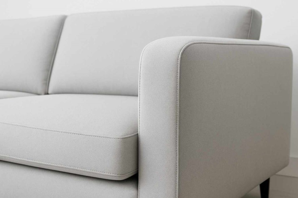 Close-up view of a light grey upholstered sofa with clean stitching and smooth finishing