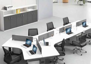 Modern open-plan office setup with white workstations, ergonomic chairs, laptops, and a storage cabinet in a clean, minimal workspace