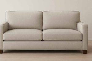 Beige upholstered two-seater sofa with clean lines and cushioned seats placed against a neutral wall
