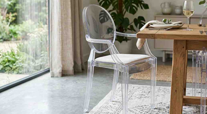 Transparent acrylic dining chair placed beside a wooden dining table in a modern setting