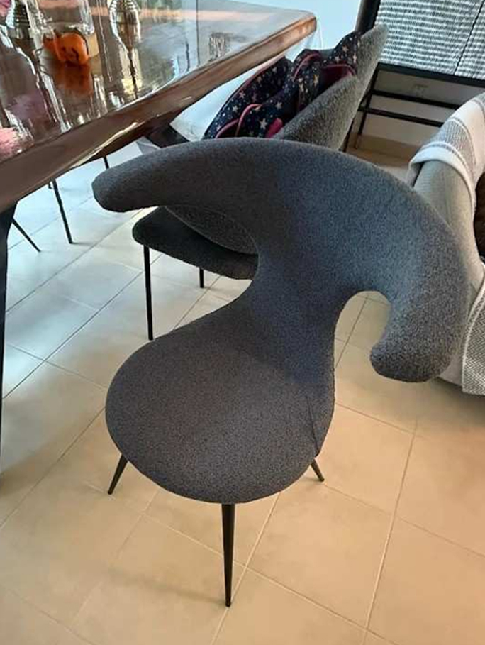 Modern upholstered dining chair with curved backrest and textured fabric in contemporary style