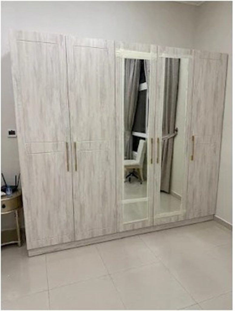 Modern white wooden wardrobe with mirrored doors and multiple storage compartments in a minimalist bedroom interior