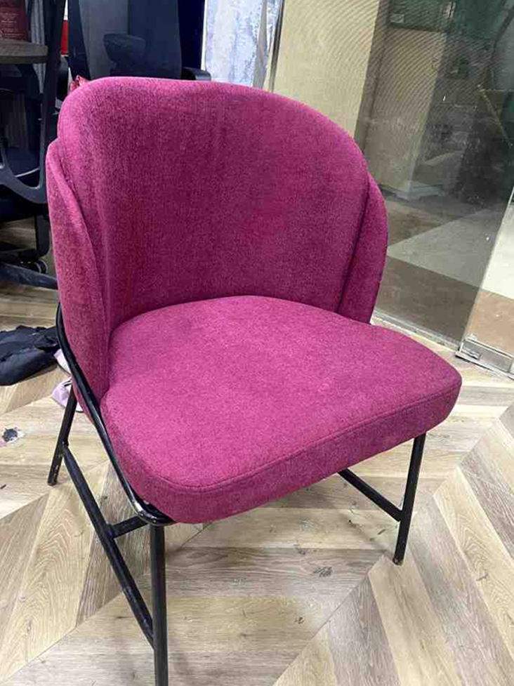 A magenta-colored accent chair with a curved backrest and slim black metal legs.