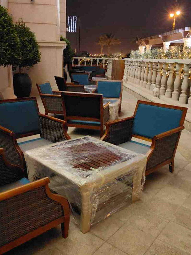 Outdoor wicker lounge chairs with cushions arranged around coffee table on patio