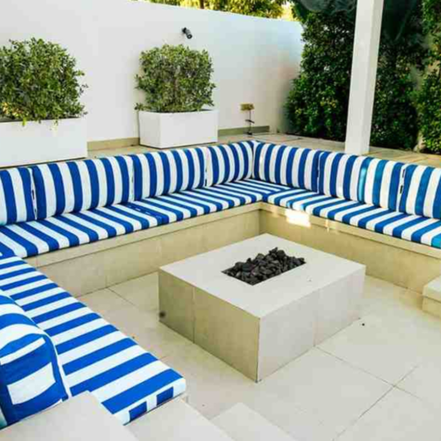 Comfortable custom made outdoor sofa seating with striped cushions around fire pit