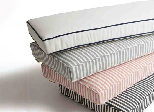 Stacked outdoor cushions and seat pads with striped fabric and thick padding