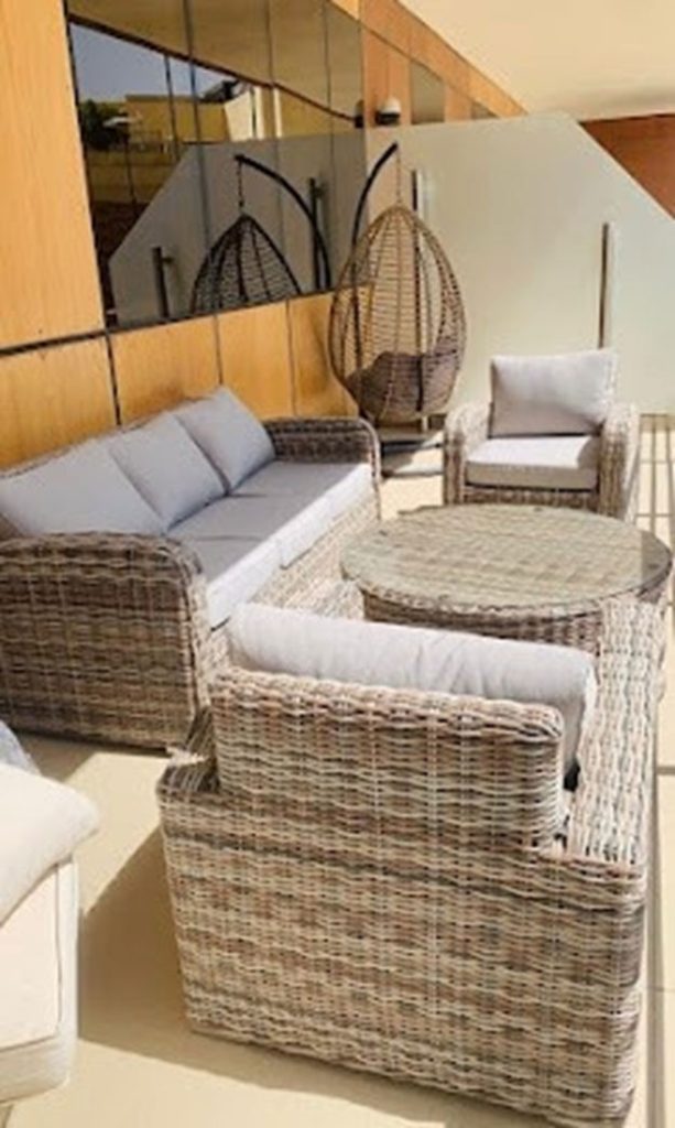 Wicker sofa set with cushioned seating and round table in outdoor space
